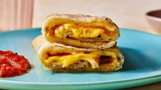 Straighton shot of a roti omelet rollup with sambal oelek on the side and american cheeze oozing out