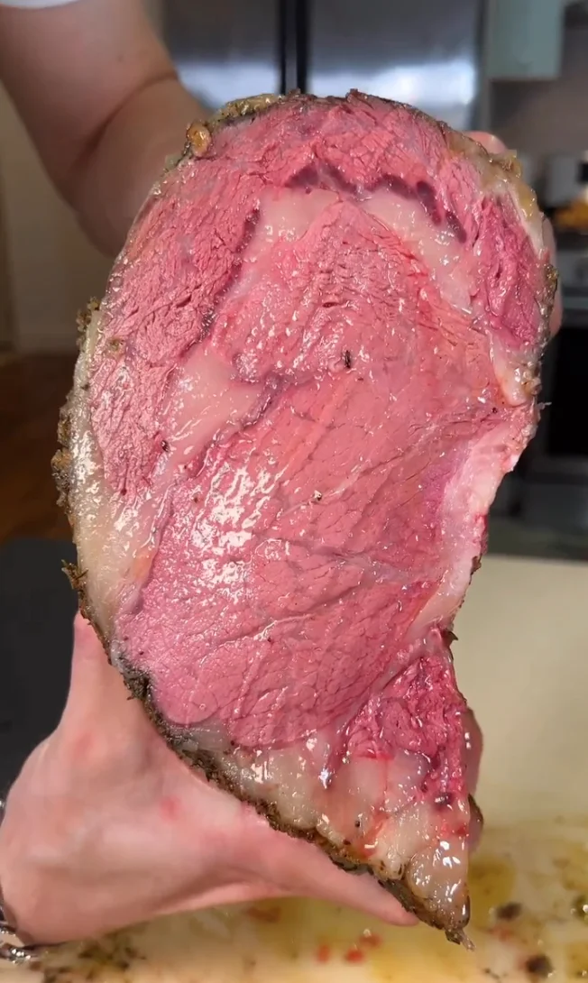Close-up of a Brooklyn holding a large, cooked piece of meat