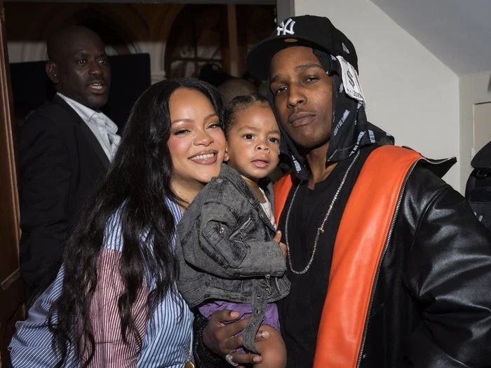 I don’t know who they are, but the image shows three people smiling and posing together at an event. A child is held between two adults