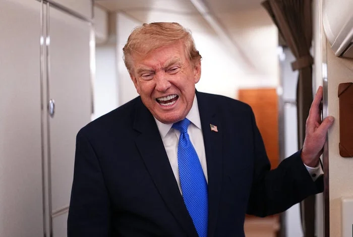 A person in a suit and tie is laughing inside an aircraft cabin