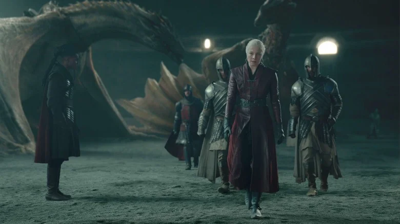Emma D'Arcy as Rhaenyra Targaryen walking away from her dragon and surrounded by guards in House of the Dragon