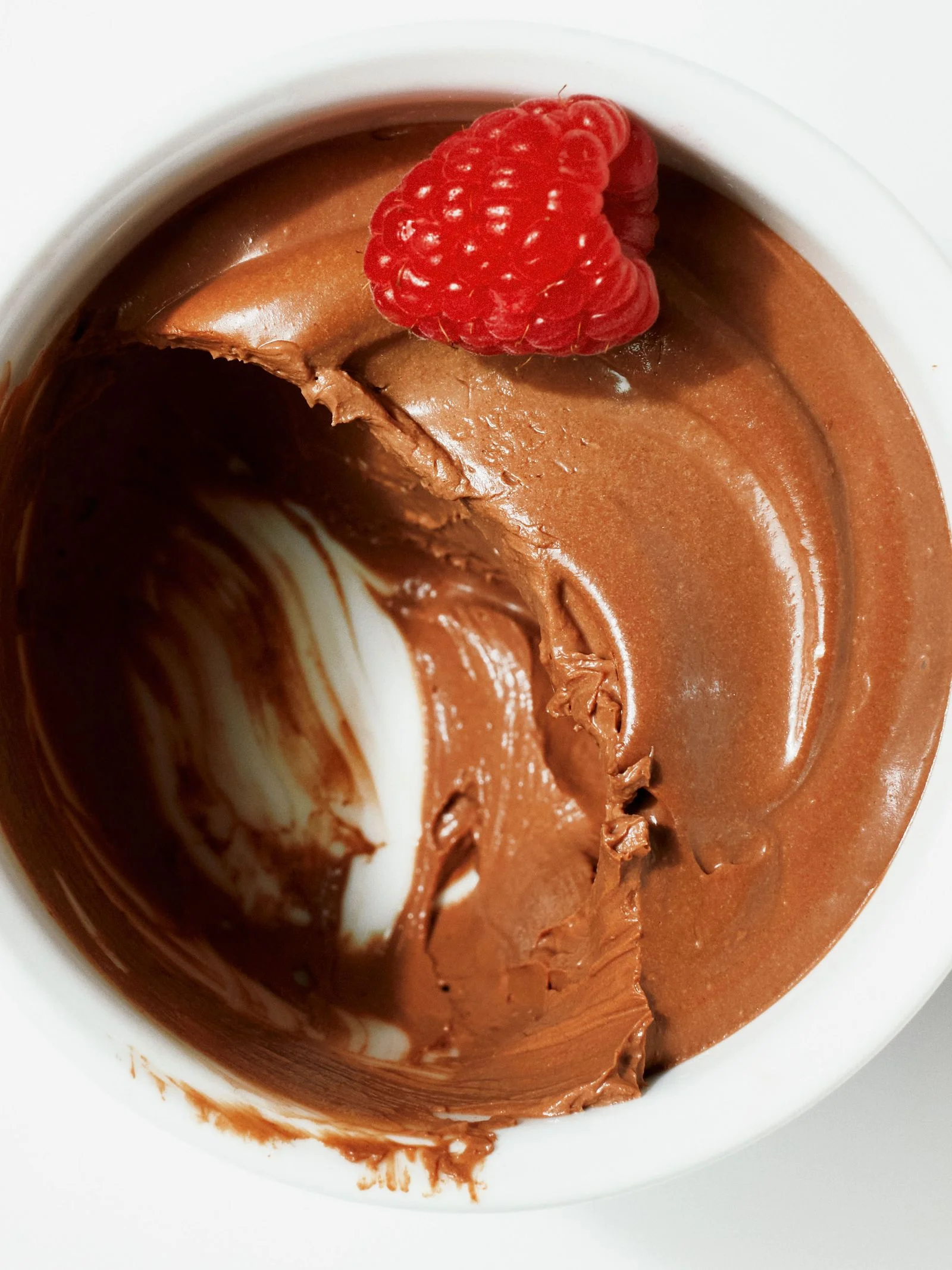 A bowl of mousse made from silken tofu and bittersweet chocolate chips topped with raspberries.