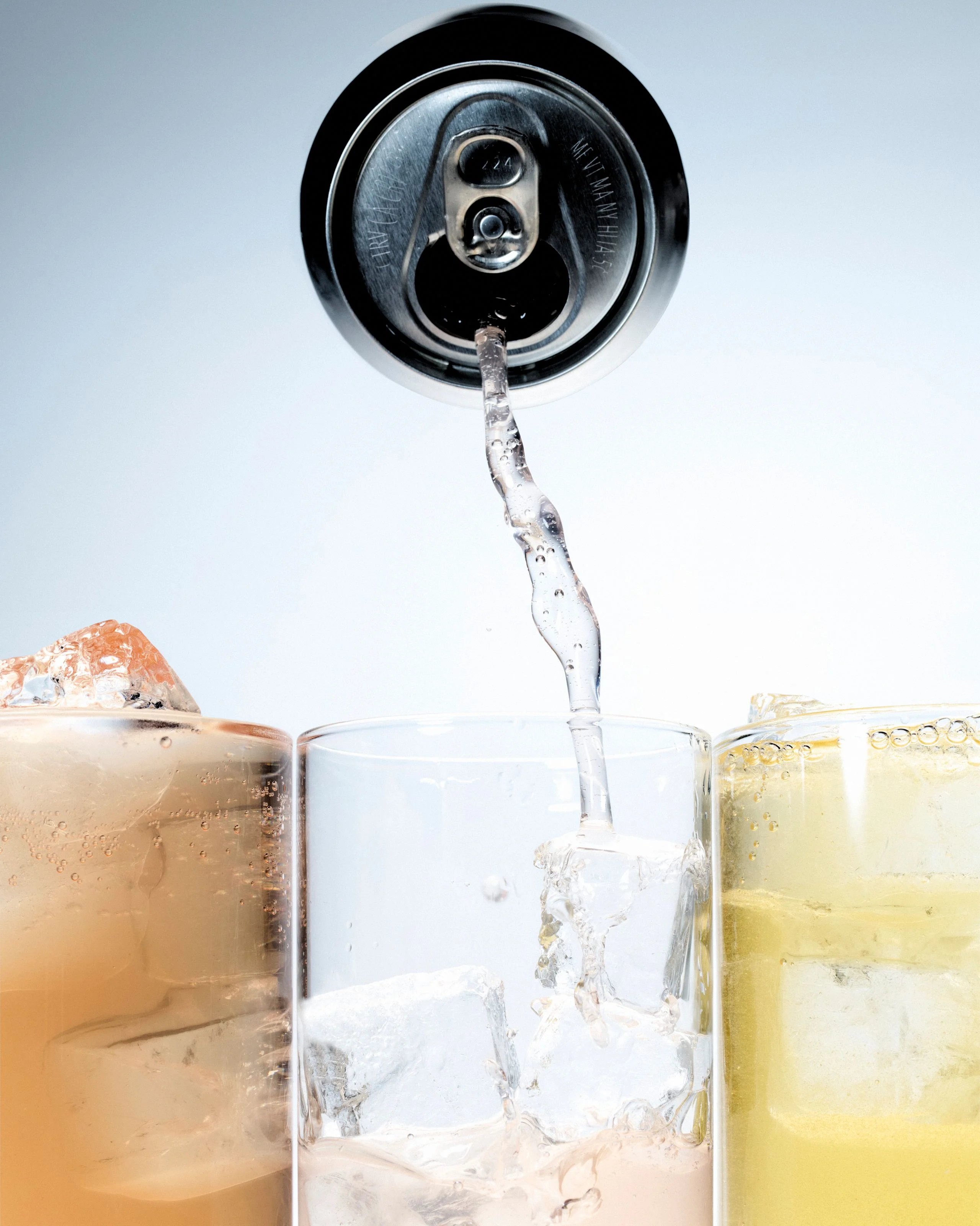 A can of  seltzer pouring into glasses
