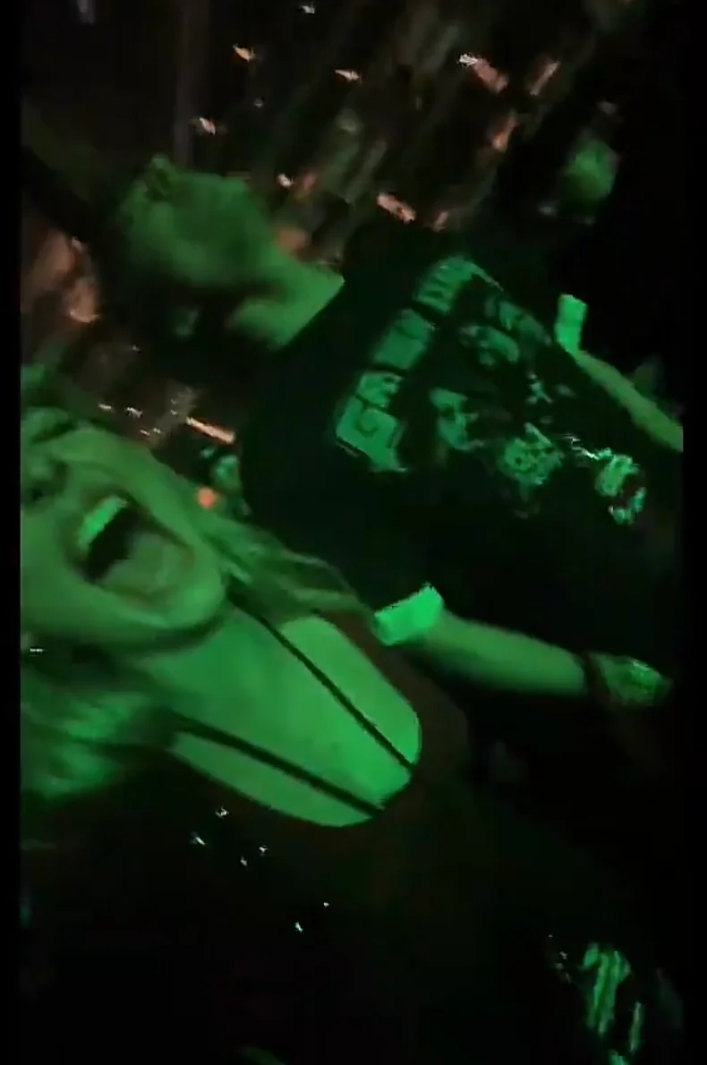 Two people enjoying a concert, one in a graphic tee. They appear enthusiastic and are surrounded by a lively crowd