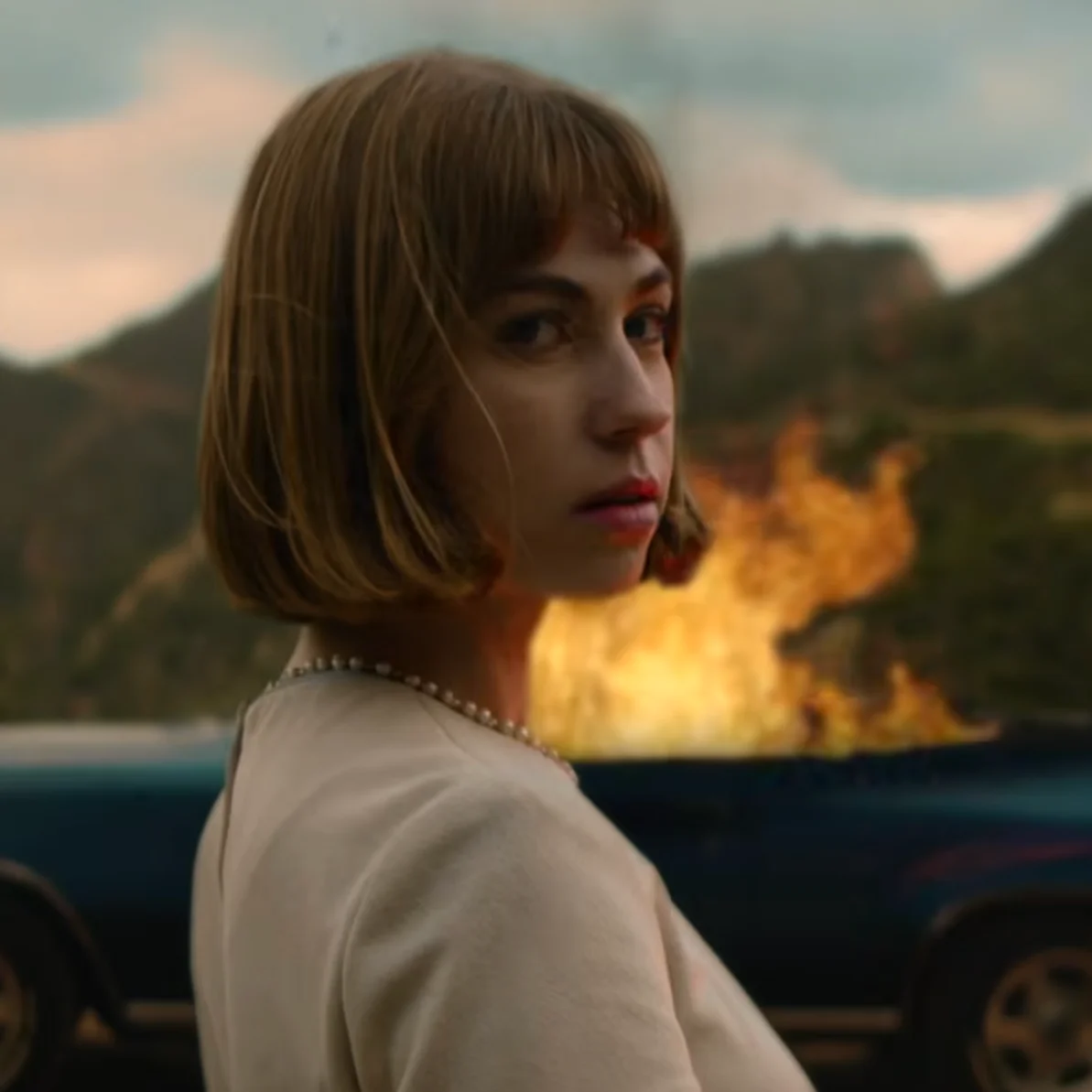 June looking at the camera as a car is in flames