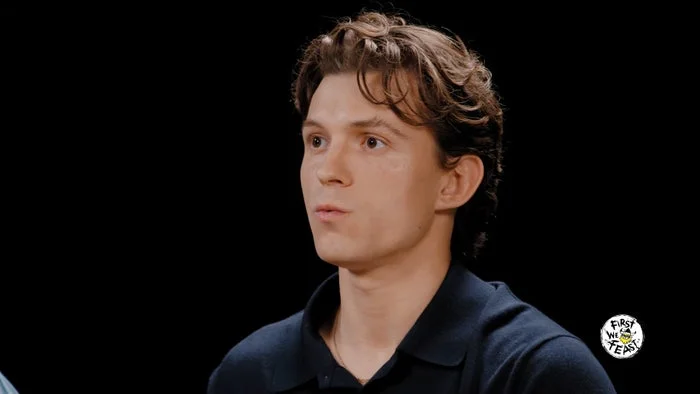 A person on a talk show, wearing a casual collared shirt, with a focused expression