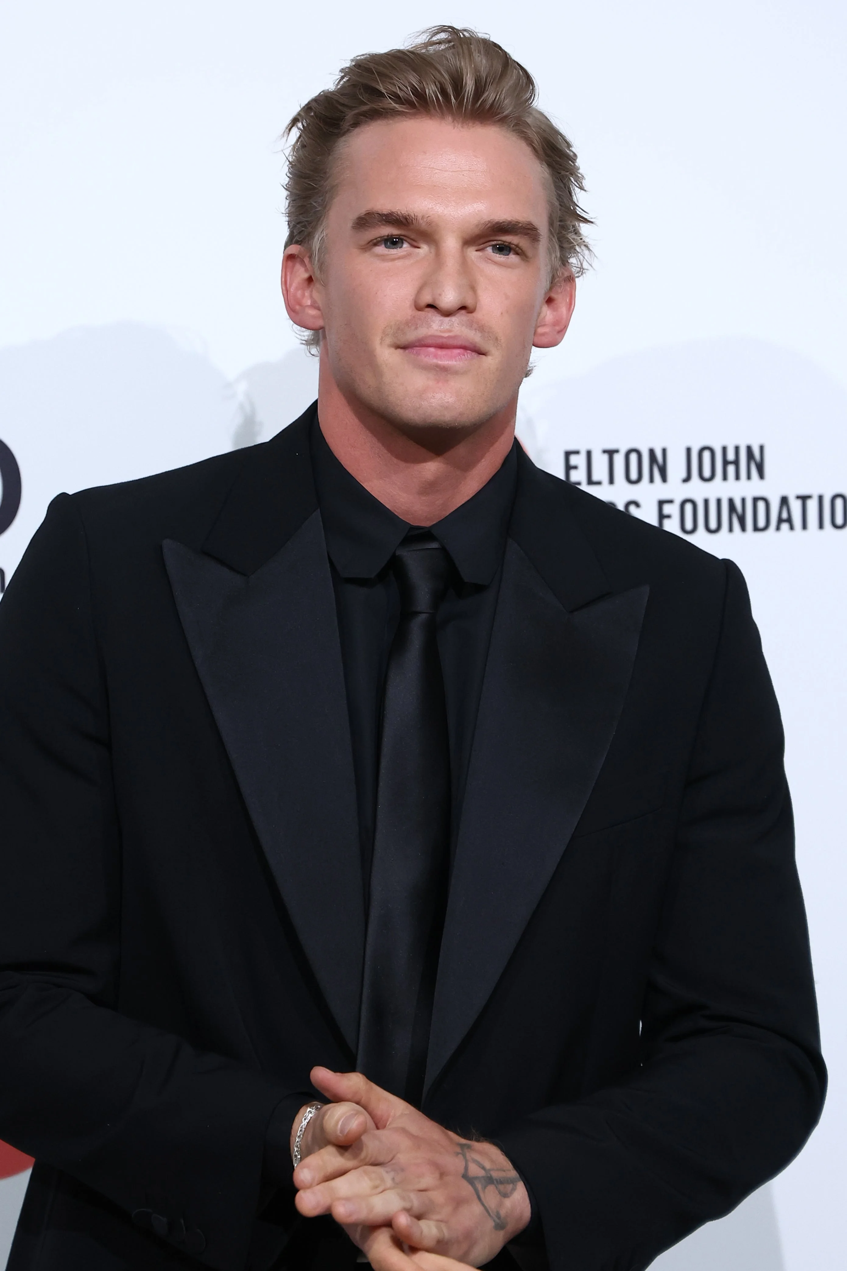 Person in a sharp black suit with a satin lapel at an Elton John AIDS Foundation event
