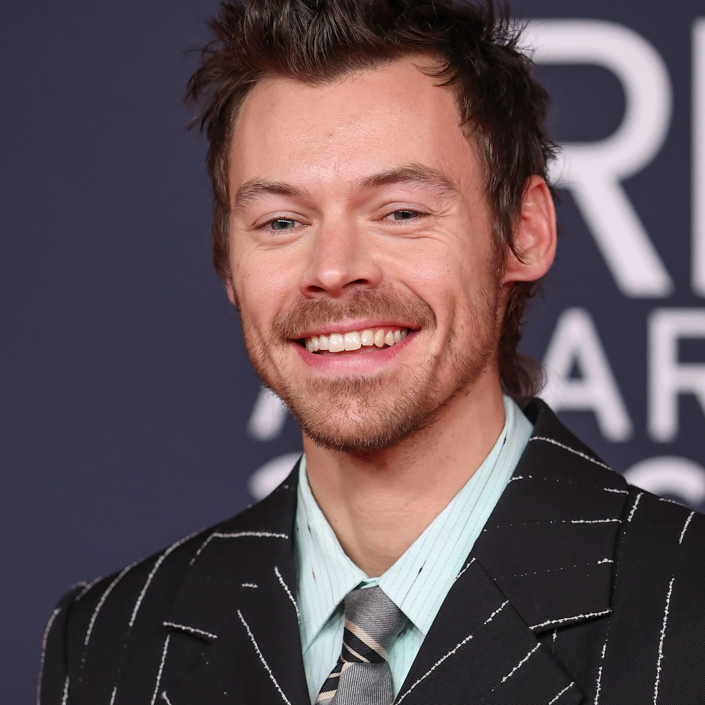 Person smiling, wearing a pinstripe suit with a tie, at a formal event