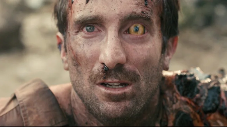 Sharlto Copley as Wikus van de Merwe staring upward (having partly transformed into an alien) in District 9