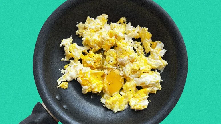 Image of frambled eggs on a frying pan against a colorful background