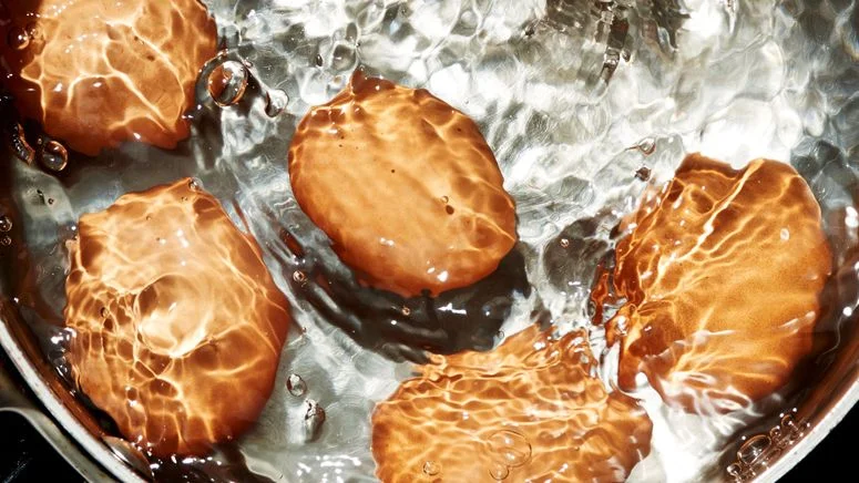 Eggs submerged in boiling water for our best hard-boiled egg recipe.