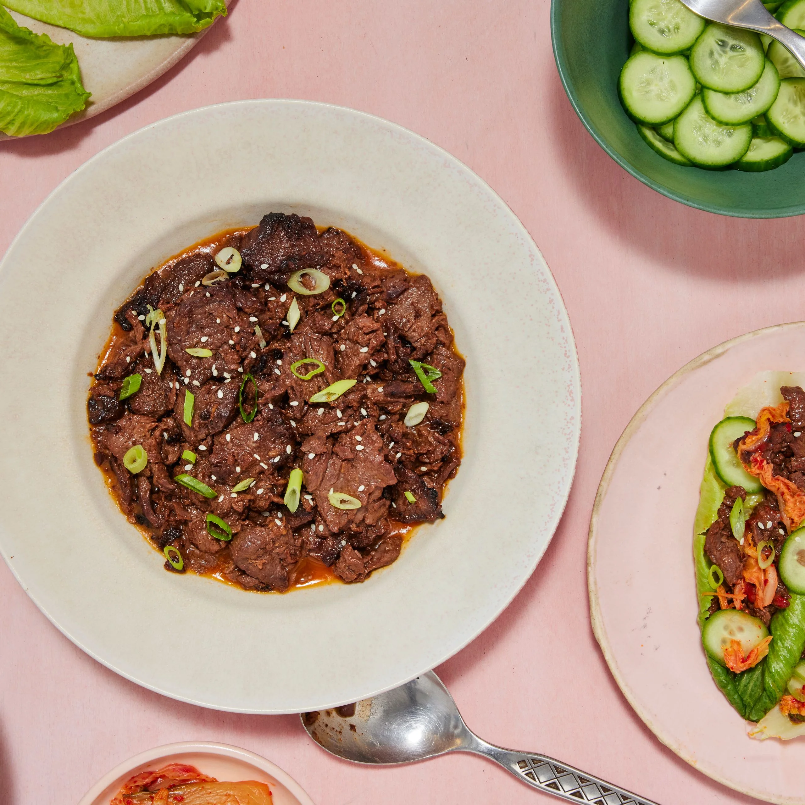 A plate of Bulgogi plated in a beige bowl on a pink surface
