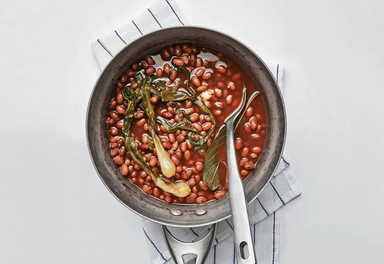 A pot of cooked dried red beans on top of a kitchen towel