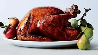 Glazed roast turkey on a platter with apples and pears.