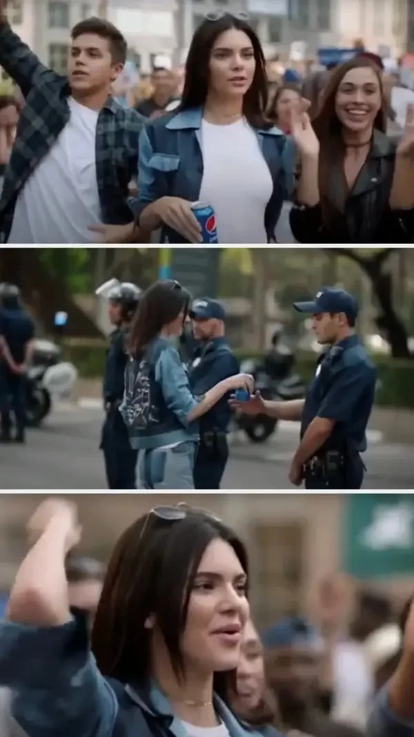 Kendall walks through a crowd of protesters and hands a cop a can of Pepsi