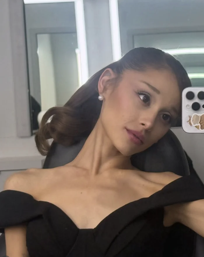 Person in an off-shoulder black gown taking a selfie in a dressing room