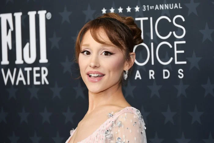 Person on red carpet in elegant dress with sequins and updo hairstyle at awards event